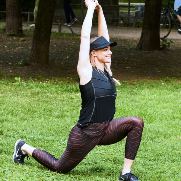 Woman wears cooling shirt from E.COOLINE and does stretching exercises outside
