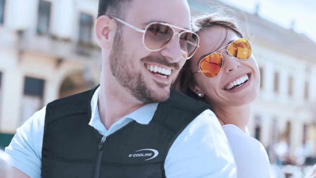 Junges Paar in Rom. Beide lachen ind ie Kamera. Der Mann trägt eine Ecooline-Kühlweste