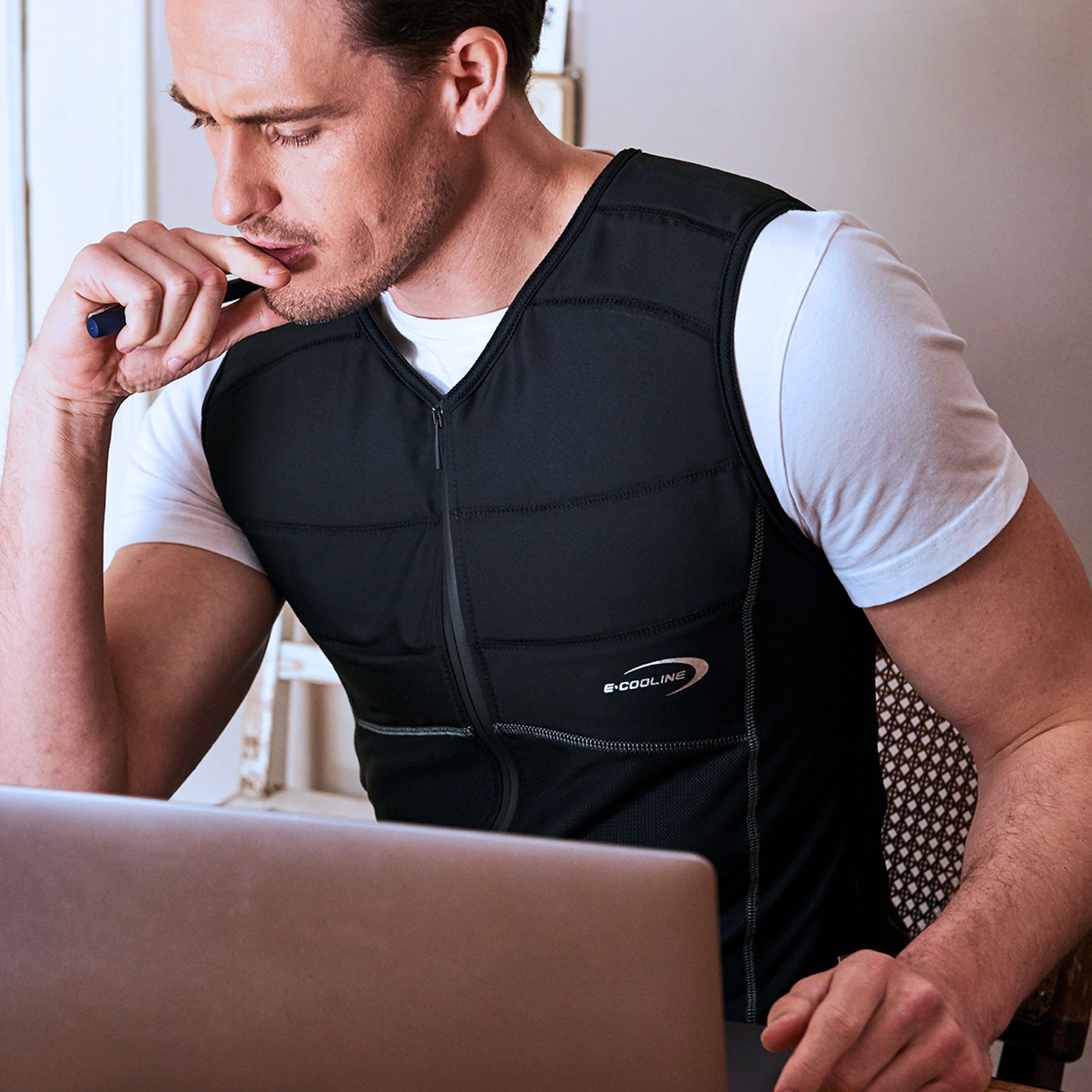 Man wearing cooling shirt from E.COOLINE in black and working on laptop
